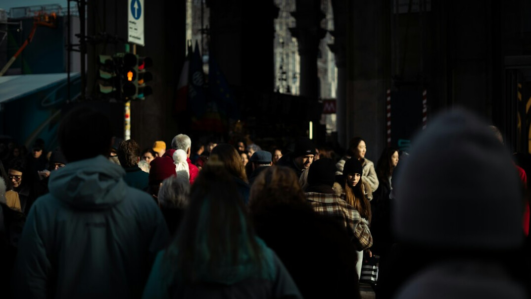 Anonymous crowd of people seen from a distance in soft evening light